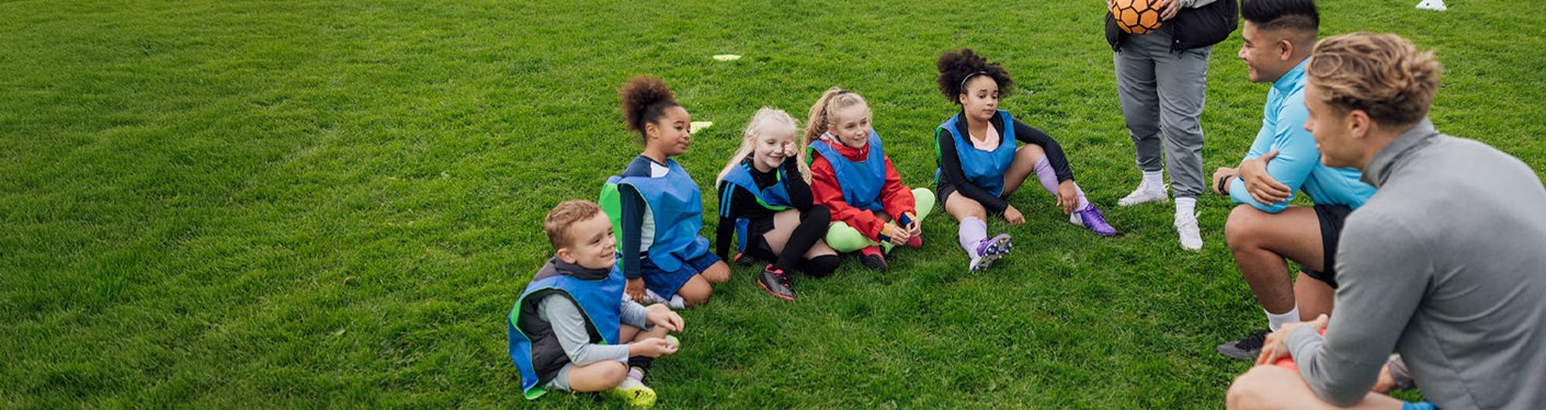 Football coaches talking to a group a children