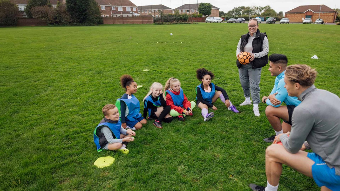 Football coaches talking to a group a children