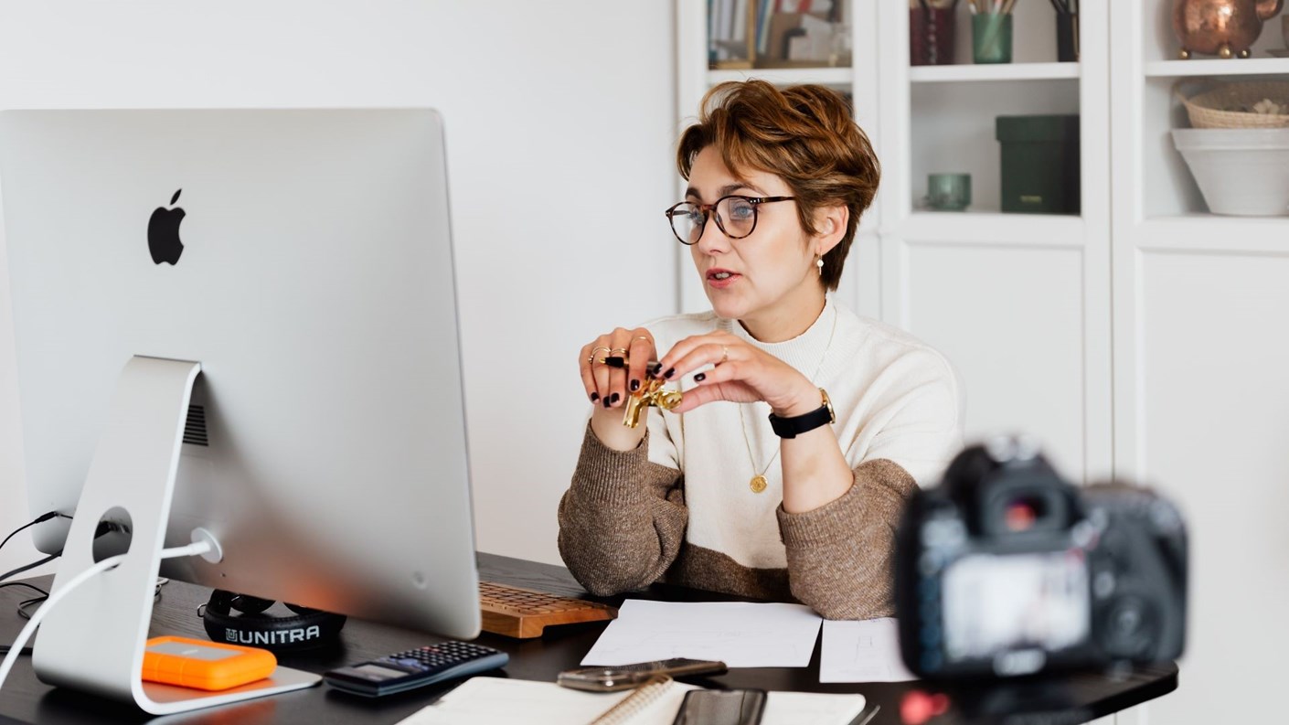 Woman working at her computer while being filmed by a camera