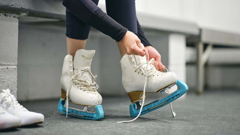 Person putting a pair of ice skating boots on